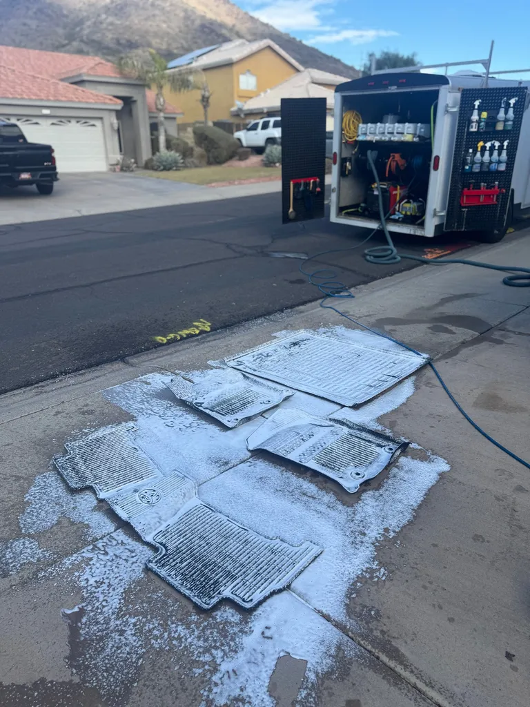 Floor mats being scrubbed next to the Dynamic Pro mobile detailing trailer