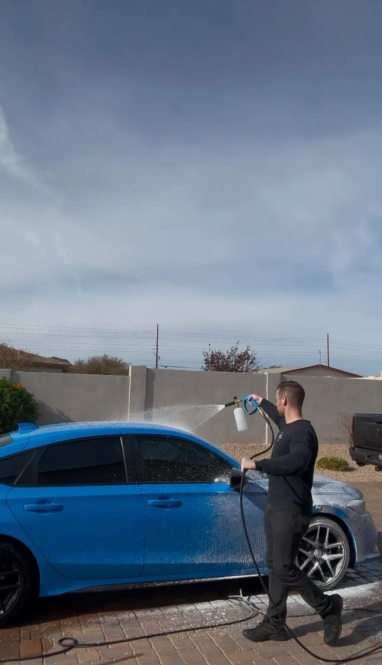 Foam cannon pre-wash on a blue sedan during an exterior detail