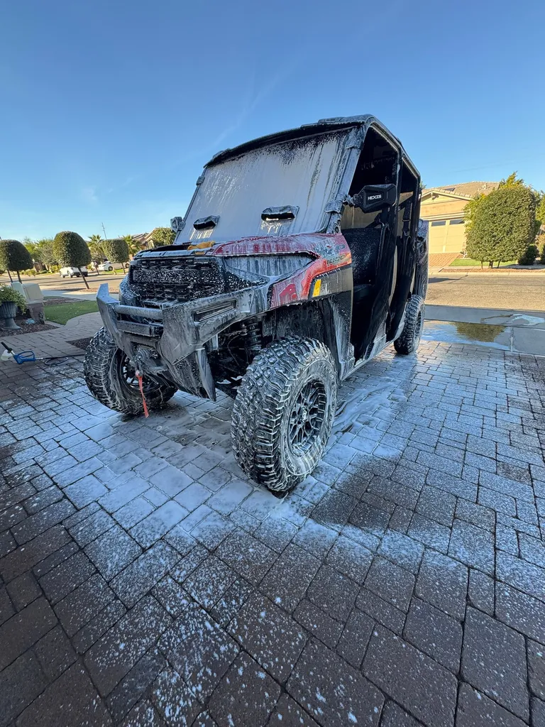 Side-by-side UTV covered in foam during a wash on a paver driveway